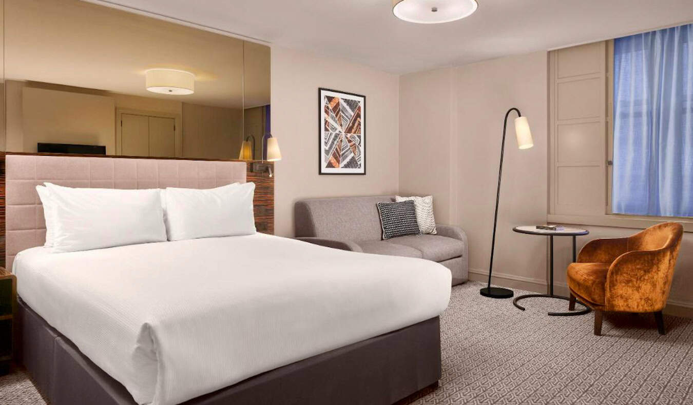 Ένα φωτεινό, μινιμαλιστικό δωμάτιο ξενοδοχείου με ένα μεγάλο κρεβάτι στο Strand Palace Hotel στο Λονδίνο, Ηνωμένο Βασίλειο