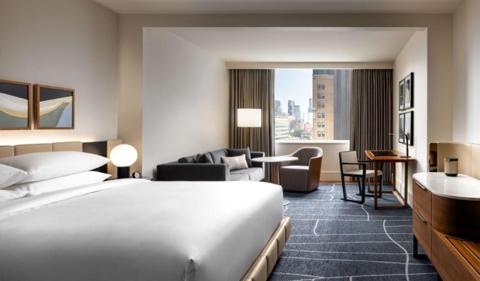 Ένα μεγάλο δωμάτιο με κρεβάτι king-size, καναπέ, καθιστικό, μεγάλα παράθυρα, όλα διακοσμημένα με μινιμαλιστικό μοντέρνο ντιζάιν στο ξενοδοχείο Park Hyatt στο Τορόντο του Καναδά