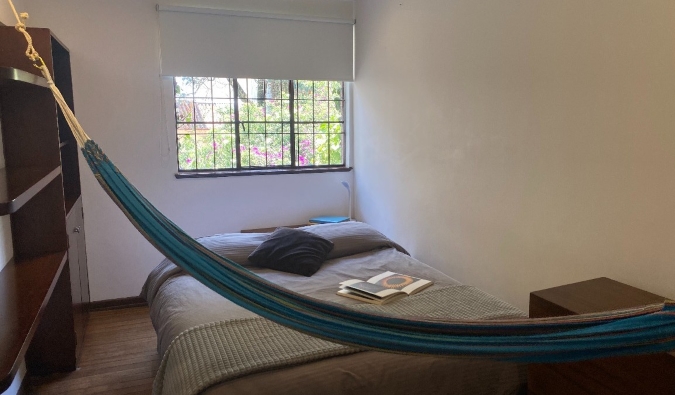 Απλό δωμάτιο στο Magdalena Guest House στην Μπογκοτά της Κολομβίας, με διπλό κρεβάτι, ξύλινη ντουλάπα, παράθυρο και αιώρα σε όλο το δωμάτιο